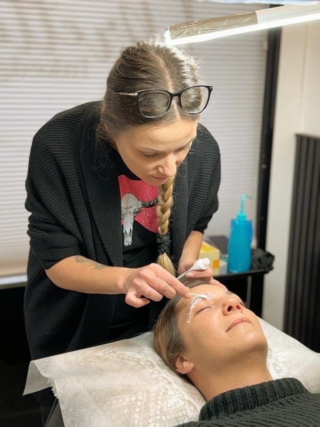 A woman receiving an eyebrow tattoo, enhancing her natural appearance with precise and professional cosmetic procedures for fuller, well-defined eyebrows.